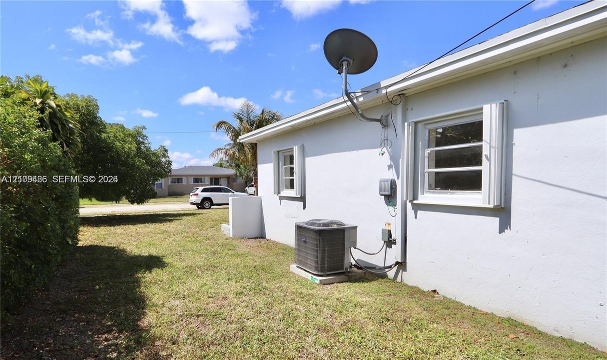 Exterior side yard featuring a stucco finish, metal hurricane shutters, and an external HVAC condenser unit
