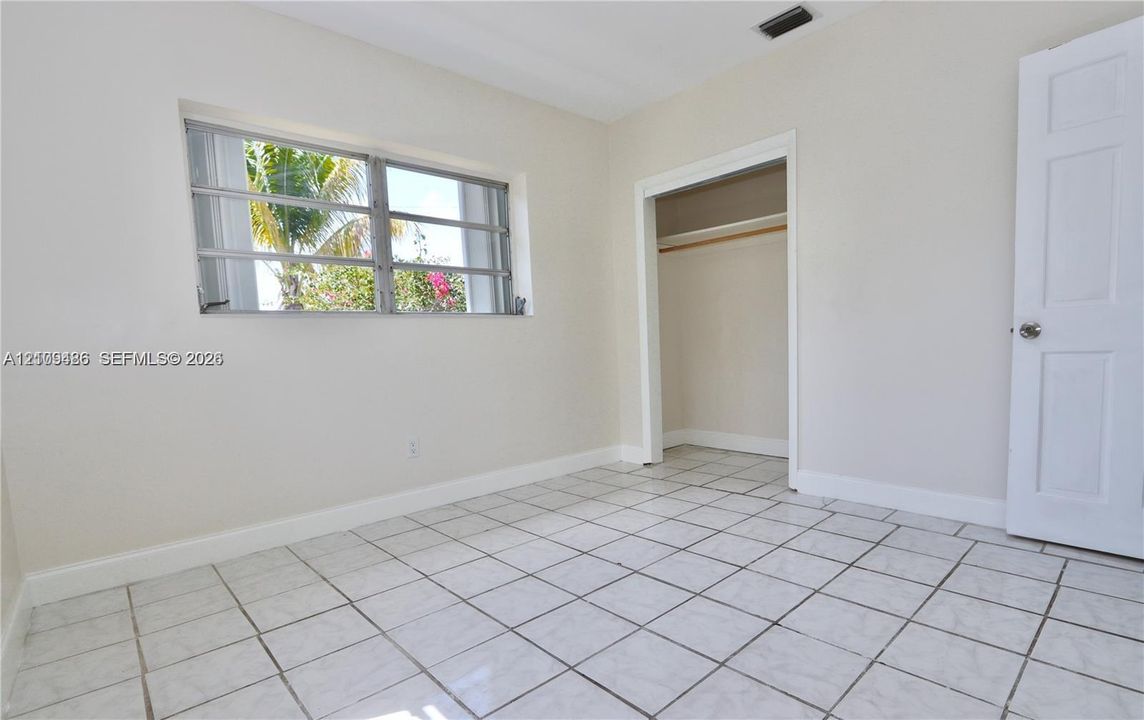 Interior space featuring ceramic tile flooring, horizontal louvered windows, and a built-in closet with a six-panel door