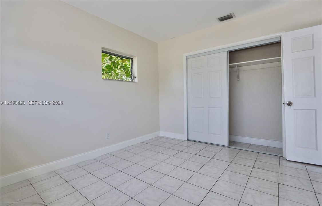 Interior space featuring tile flooring, a horizontal rectangular window, and a built-in closet with sliding panel doors