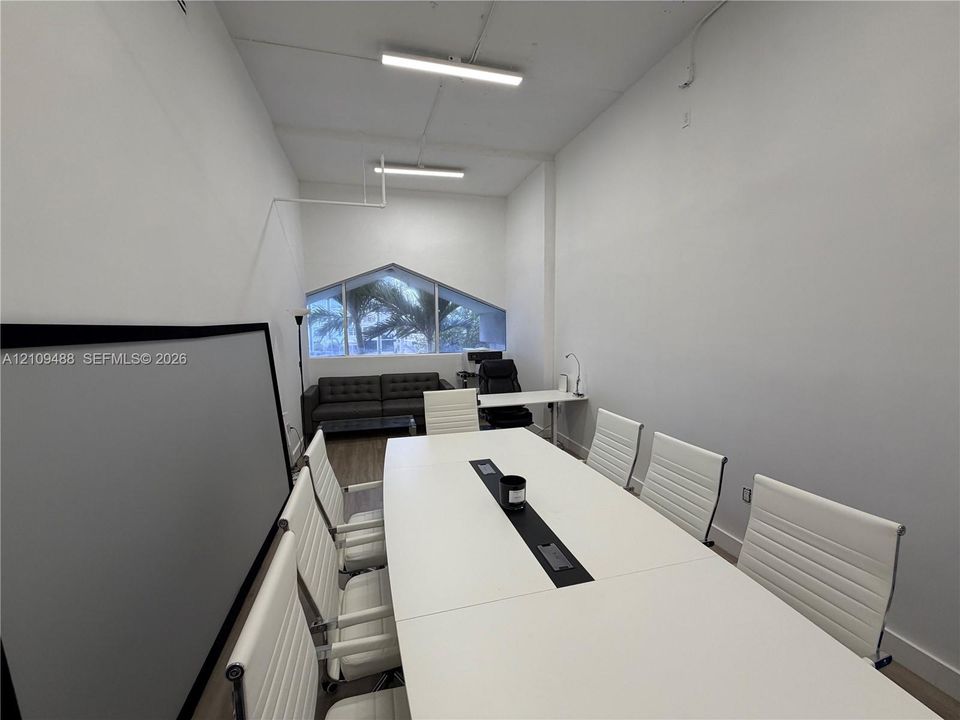 High-ceiling interior featuring wood-finish flooring, linear LED lighting, and a prominent angular-shaped window