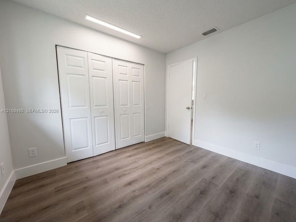 Wood-finish flooring, multi-panel bi-fold closet doors, and integrated linear LED ceiling lighting