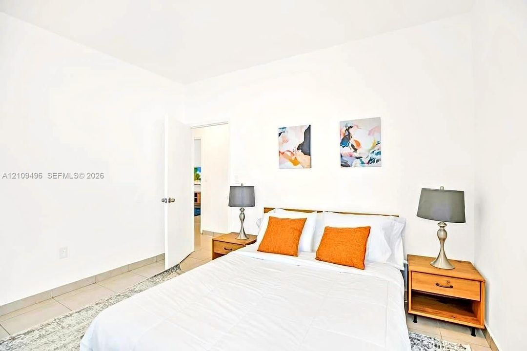 Neutral-toned ceramic tile flooring throughout, featuring a clean, minimalist interior aesthetic with white walls and a white swing door