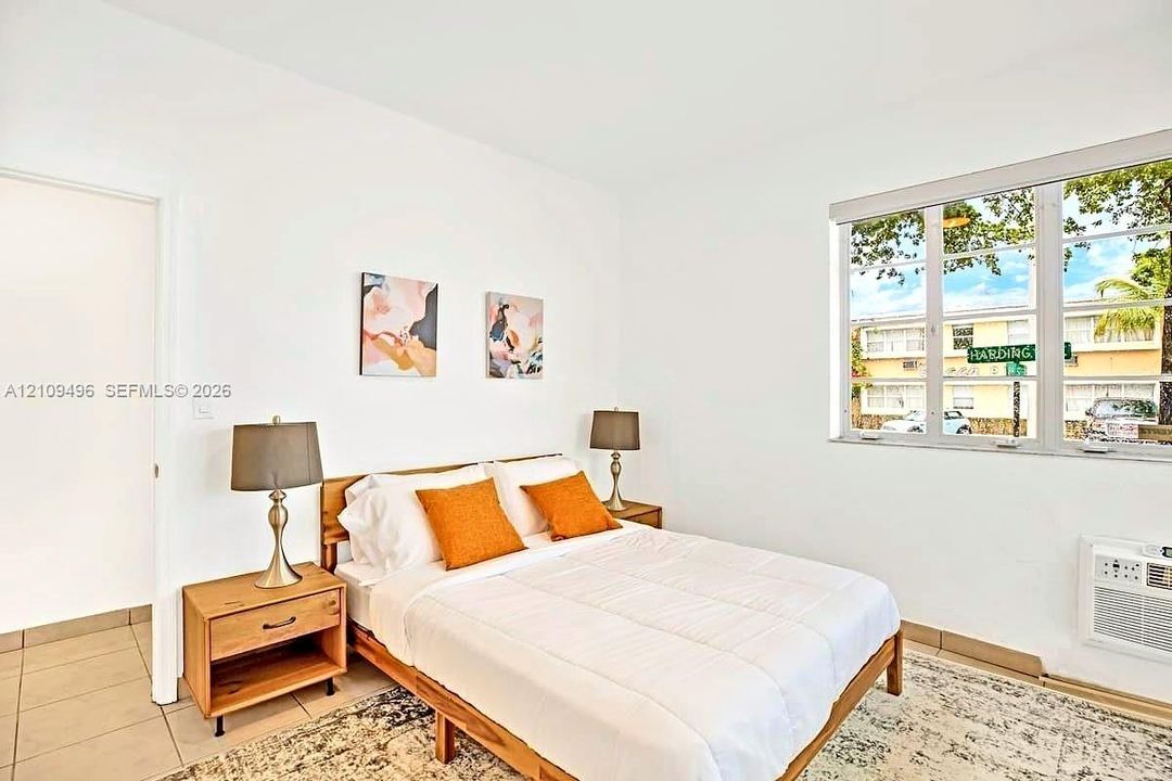 Interior room featuring neutral wall finishes, tile flooring, multi-pane window, and wall-mounted climate control unit