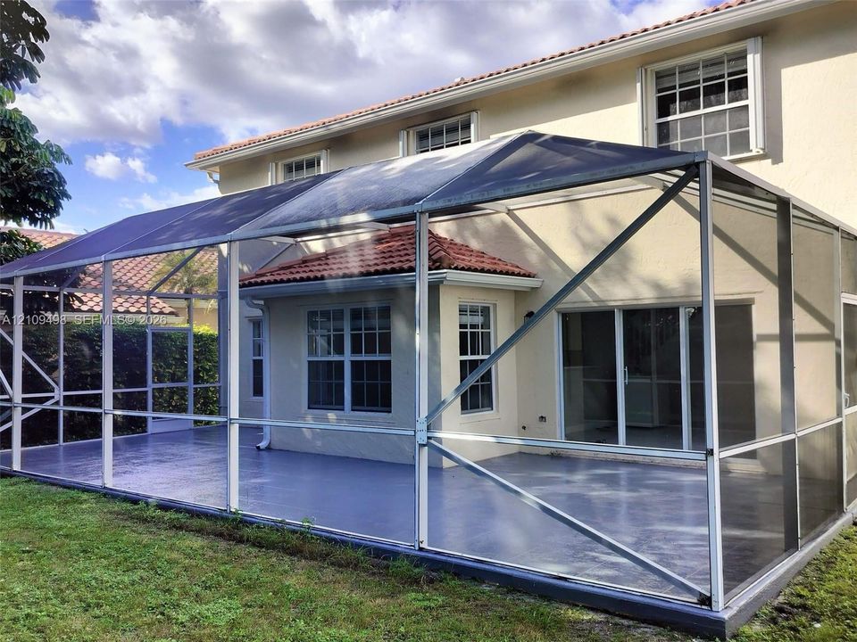 Screened-in outdoor patio featuring a painted concrete floor, metal framing, multiple-pane windows, and stucco exterior walls