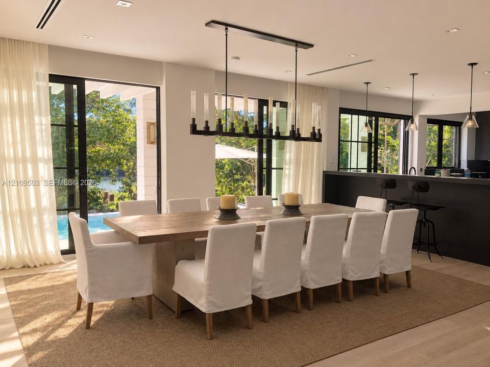 Dining area featuring large-format sliding glass doors, a linear wrought iron chandelier, recessed lighting, wood-finish flooring, and a built-in kitchen island
