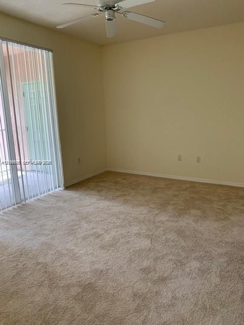 Interior room featuring wall-to-wall carpeting, a ceiling fan, and sliding glass doors with vertical blinds