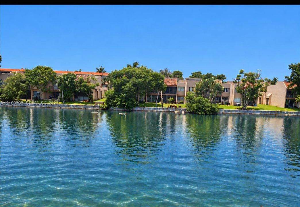 Waterfront exterior featuring multi-story dwellings, tile roofing, private seawall, and established landscaping