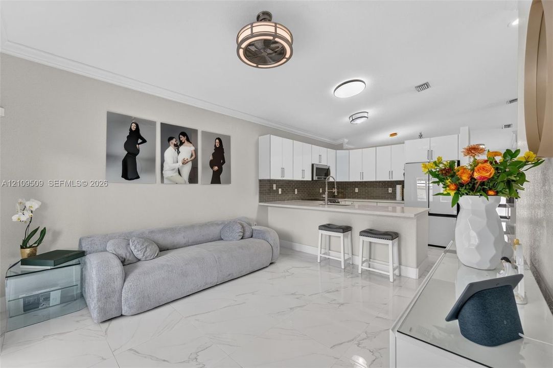 Kitchen featuring white cabinetry, quartz countertops, a stone tile backsplash, and a breakfast bar