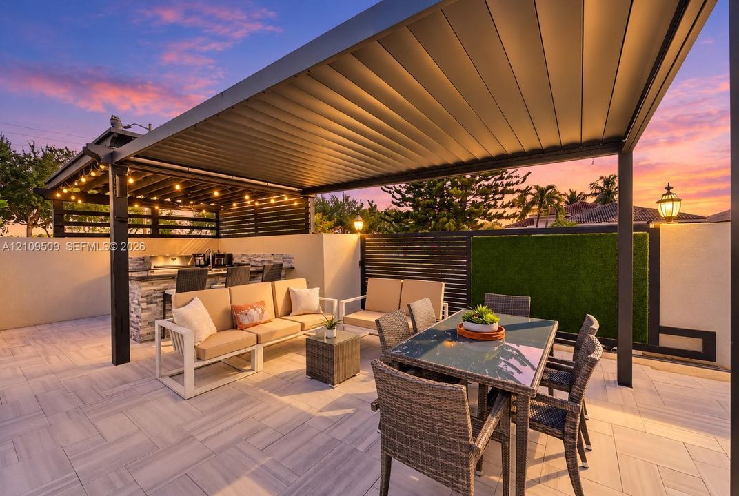 Outdoor living area featuring a covered pergola, stone-veneer wet bar with built-in grill, herringbone-patterned tile patio, and vertical wall-mounted greenery
