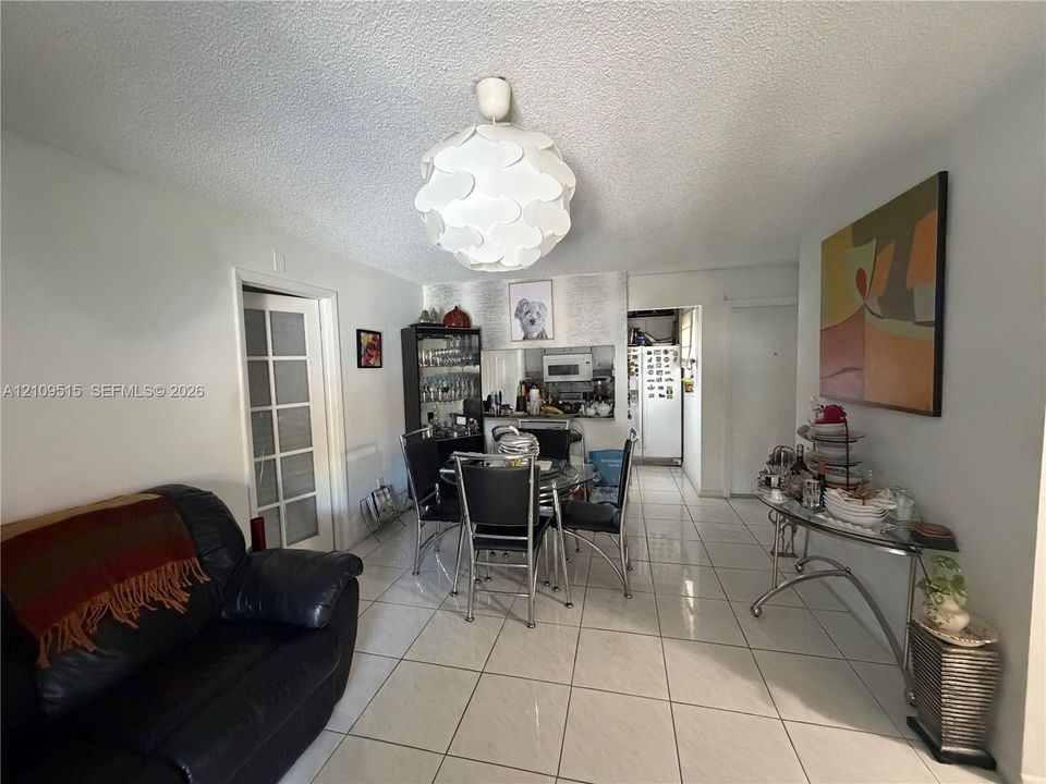Large-format tile flooring, textured ceilings, white multi-pane glass door, and a spherical sculptural pendant light fixture