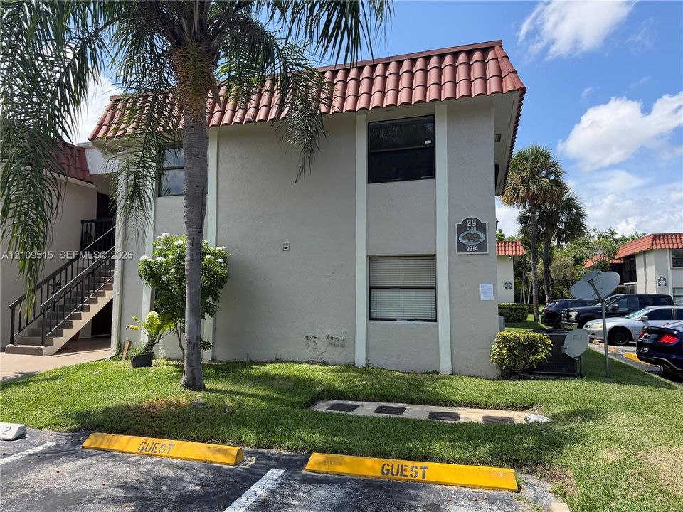 Two-story exterior featuring a clay tile roof, stucco siding, and an external staircase