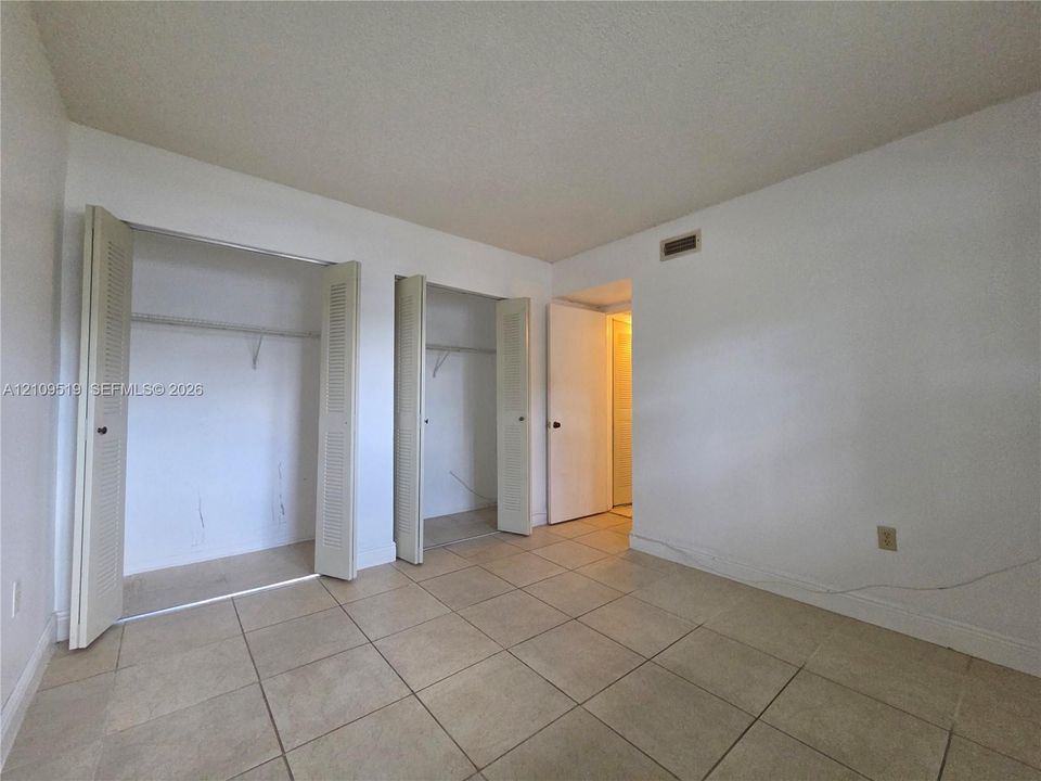 Ceramic tile flooring, louvered bi-fold closet doors, and flush-mount ceiling lighting