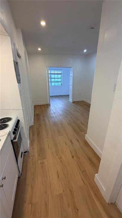 Wood-finish flooring, recessed ceiling lighting, white cabinetry, integrated electric range, and French doors