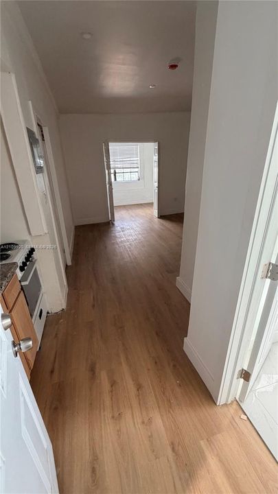 Wood-finish flooring throughout, white interior walls, and French doors leading to a secondary room