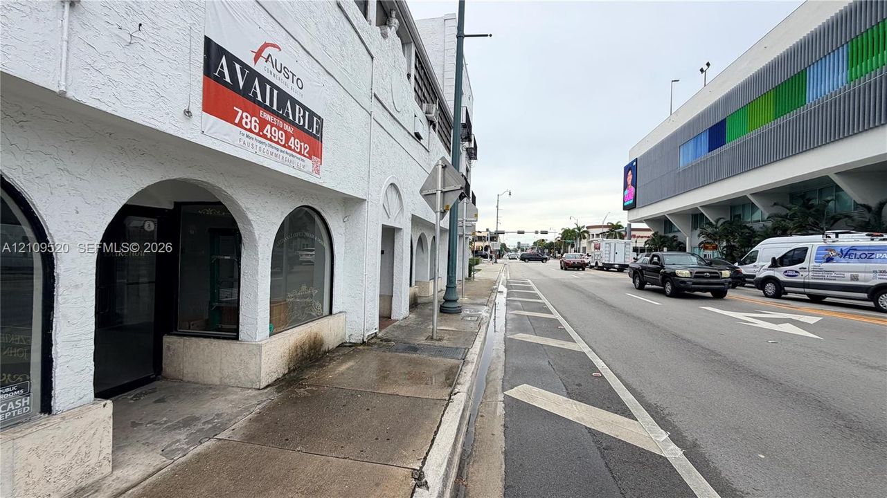 Stucco commercial facade featuring prominent arched storefront entries, recessed display windows, and direct sidewalk access