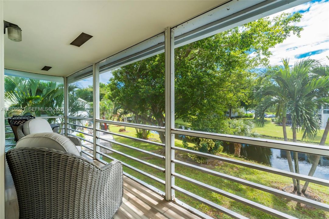 Screened-in balcony featuring metal railing, tiled flooring, recessed lighting, and water frontage