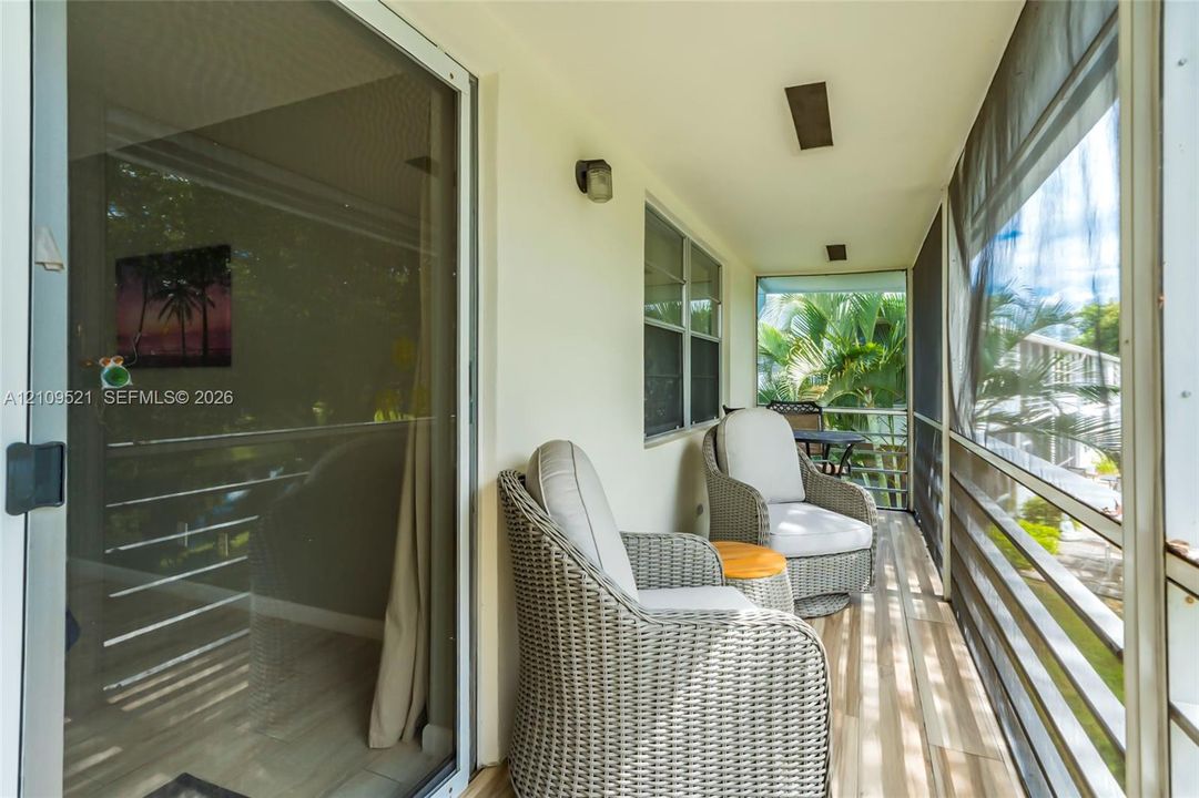 Screened-in balcony featuring wood-finish flooring, sliding glass door access, recessed lighting, and exterior wall-mounted lighting