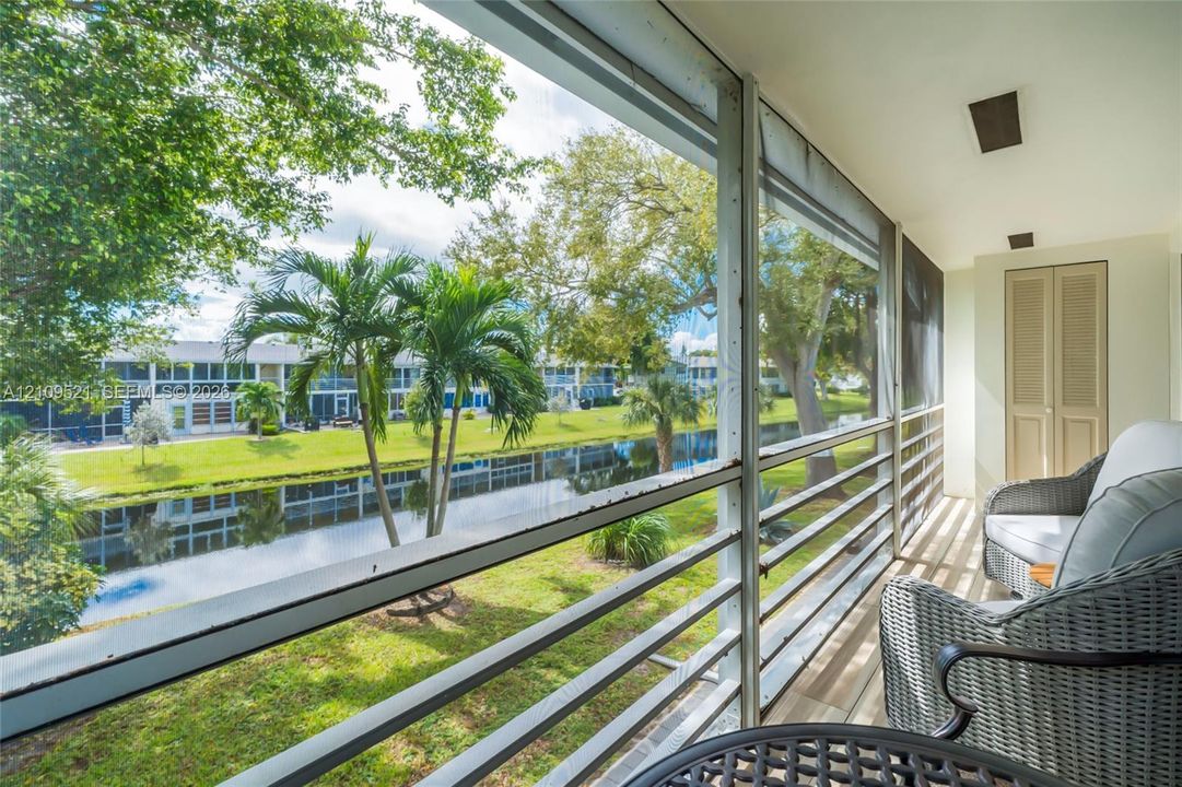 Screened-in balcony featuring wood-finish flooring, recessed lighting, louvered closet doors, and water frontage