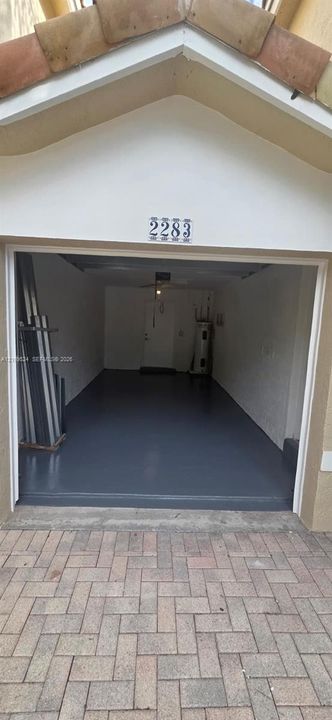 Attached garage featuring a gable roofline, painted interior walls, and finished epoxy flooring