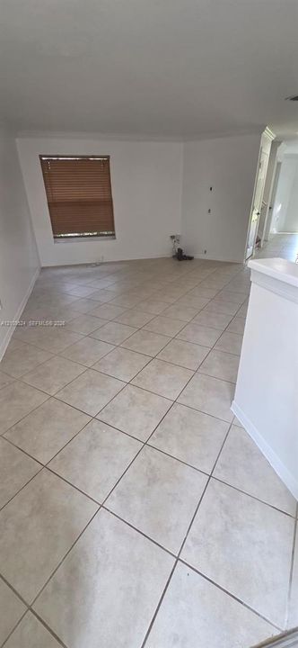 Neutral-toned ceramic tile flooring laid in a diagonal pattern, white walls, and a recessed window