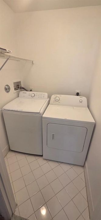 Laundry space featuring white ceramic tile flooring and overhead wire shelving