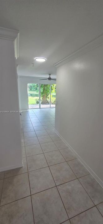 Interior hall featuring tile flooring, crown molding, a ceiling fan, and large sliding glass doors providing natural light