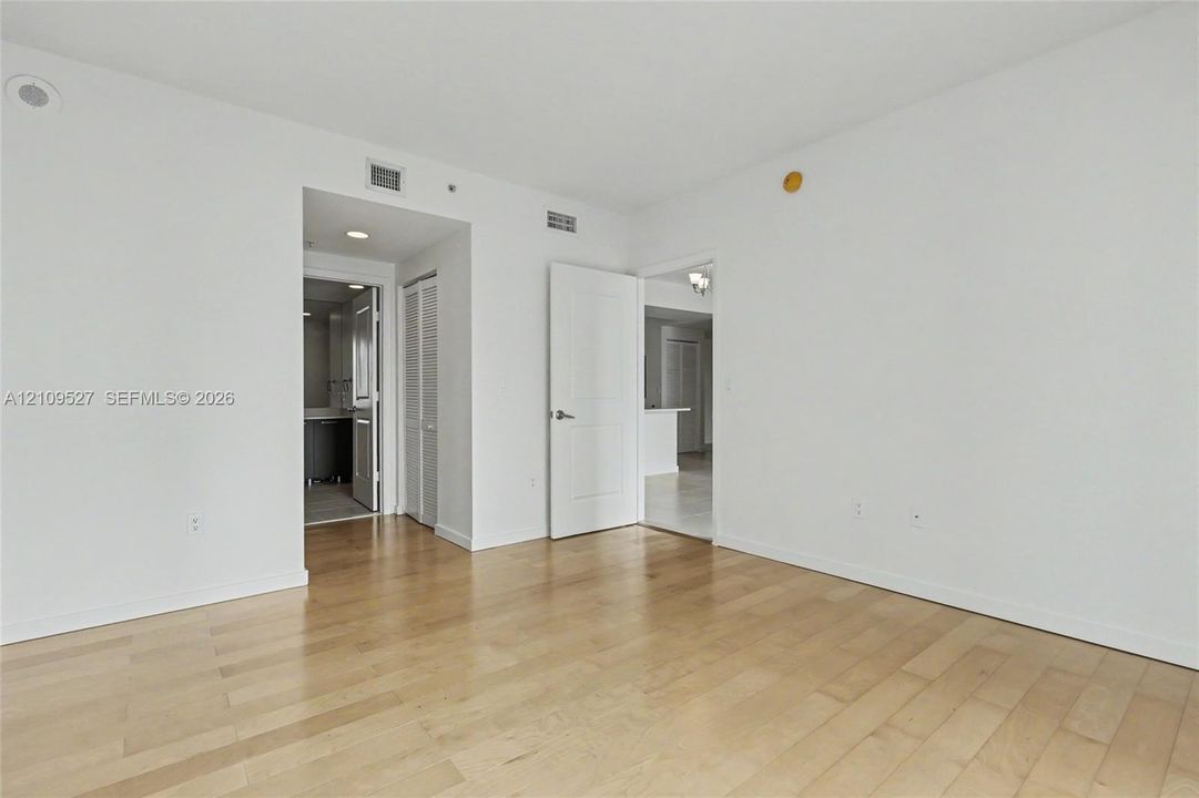 Neutral interior space featuring wood-finish flooring, crisp white walls, and solid-core interior doors