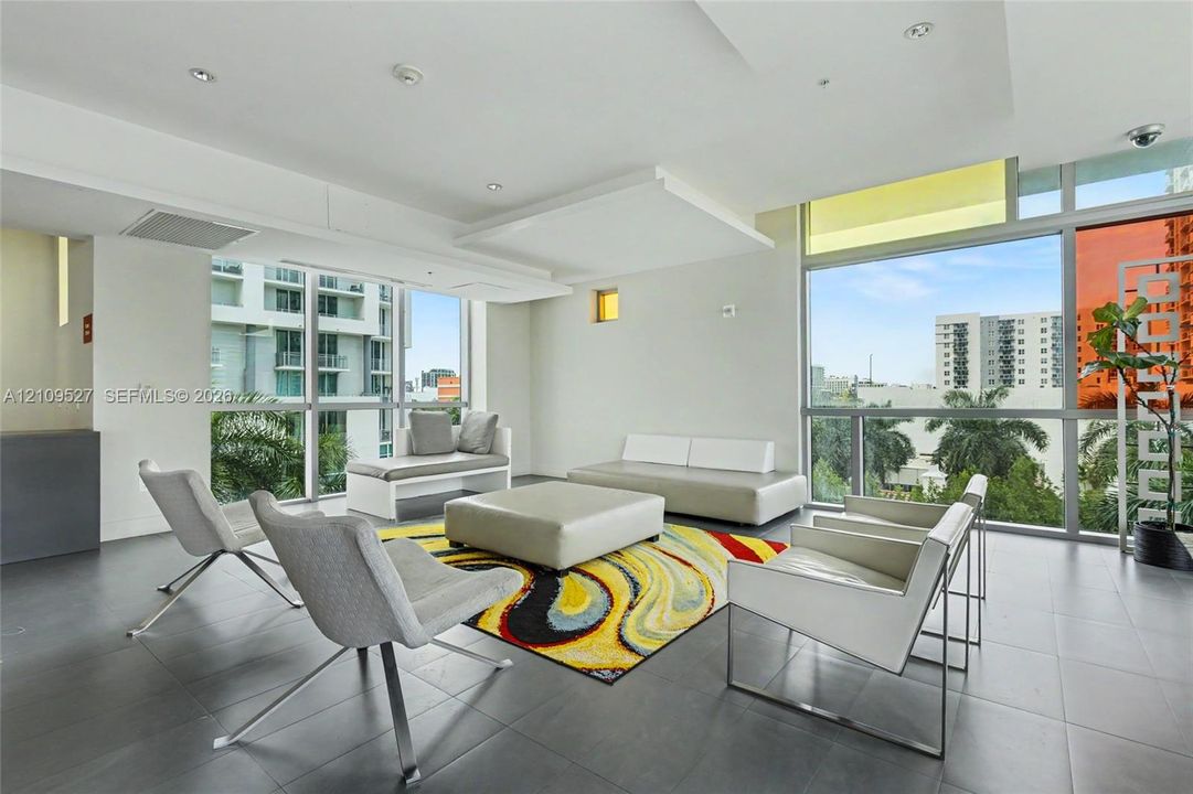 Floor-to-ceiling windows, high-contrast tile flooring, recessed ceiling lighting, and multi-level architectural ceiling panels