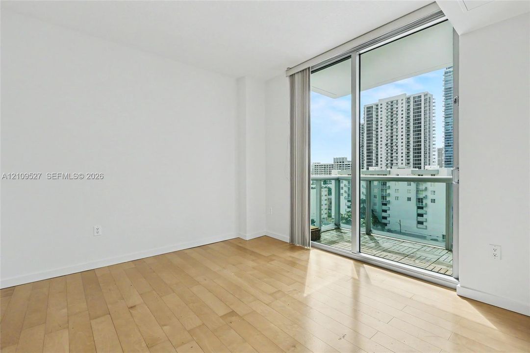 Interior space featuring wood-finish flooring, floor-to-ceiling glass sliding doors, and a private balcony with metal railings