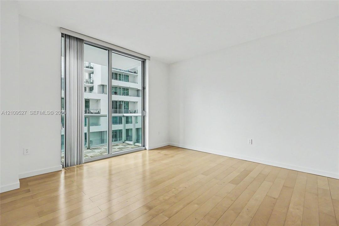 Interior space featuring wood-finish flooring, floor-to-ceiling glass sliding doors, and a private balcony
