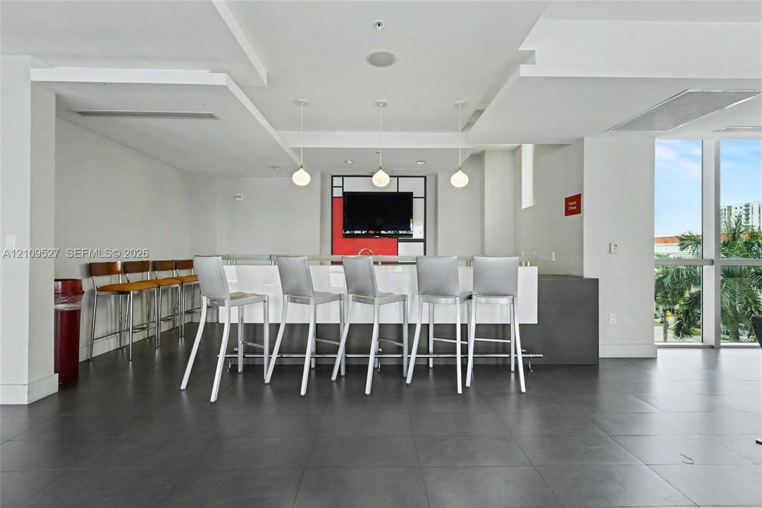 Large-format floor tile, bar-style service counter with stone surfacing, trio of spherical pendant light fixtures, recessed ceiling lighting, and floor-to-ceiling window pane