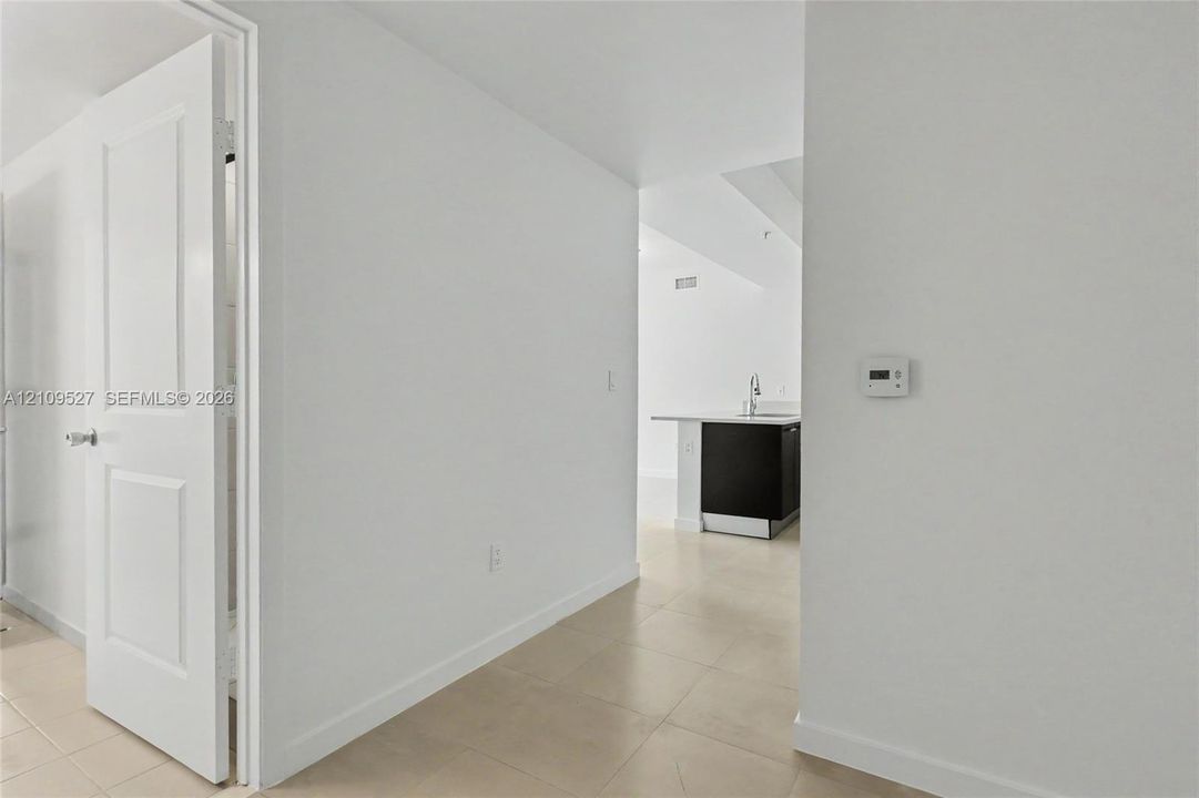 Neutral-toned ceramic tile flooring, solid-core interior doors, and minimalist wall-mounted digital thermostat
