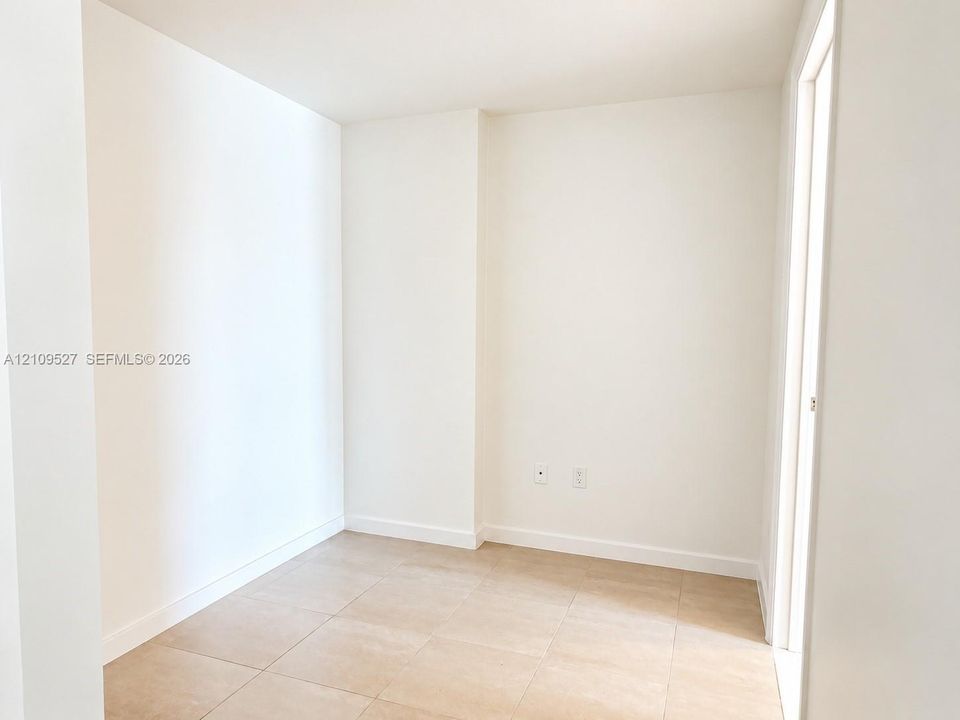 Interior room featuring neutral wall-to-wall ceramic tile flooring and smooth, white-painted walls