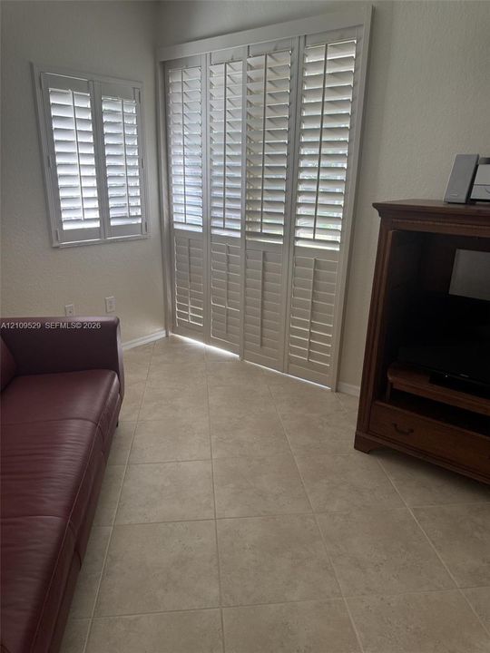 Neutral tile flooring, white plantation shutters, and large-format multi-panel sliding doors