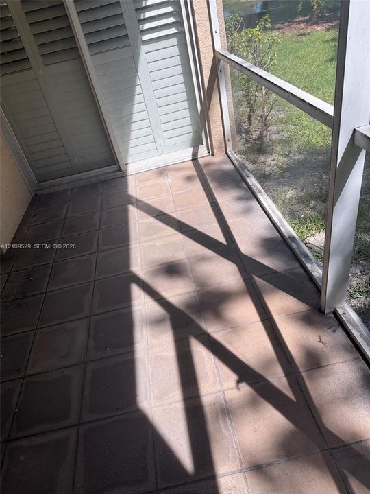 Screened-in patio featuring tile flooring and sliding glass doors with built-in shutters