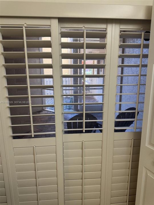 Custom off-white plantation shutters featuring adjustable louvers and integrated center tilt rods