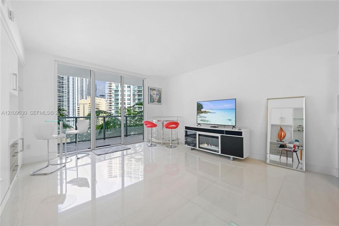 Living area featuring large-format tile flooring, floor-to-ceiling glass sliding doors, and built-in cabinetry