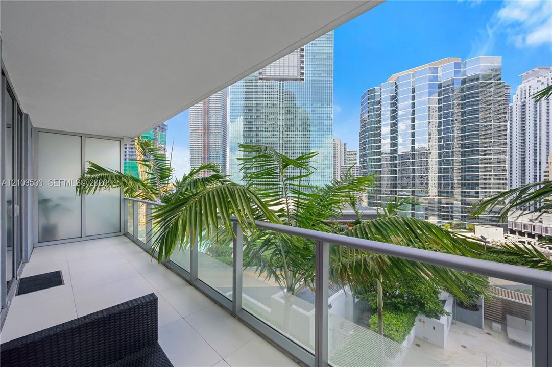 Covered balcony featuring large-format tile flooring, a glass and metal railing, and translucent privacy screening
