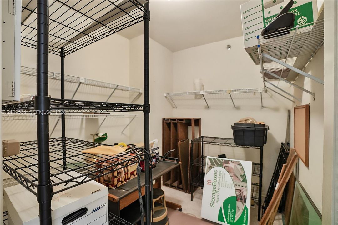 Storage area featuring white wall-mounted wire shelving and neutral wall finishes