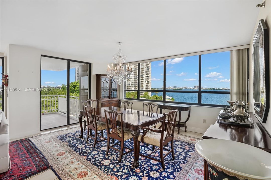 Dining area featuring floor-to-ceiling windows, porcelain tile flooring, crystal chandelier, and sliding glass doors to a private balcony