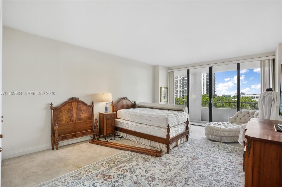Neutral interior featuring wall-to-wall carpeting and floor-to-ceiling sliding glass doors opening to a balcony with metal railings