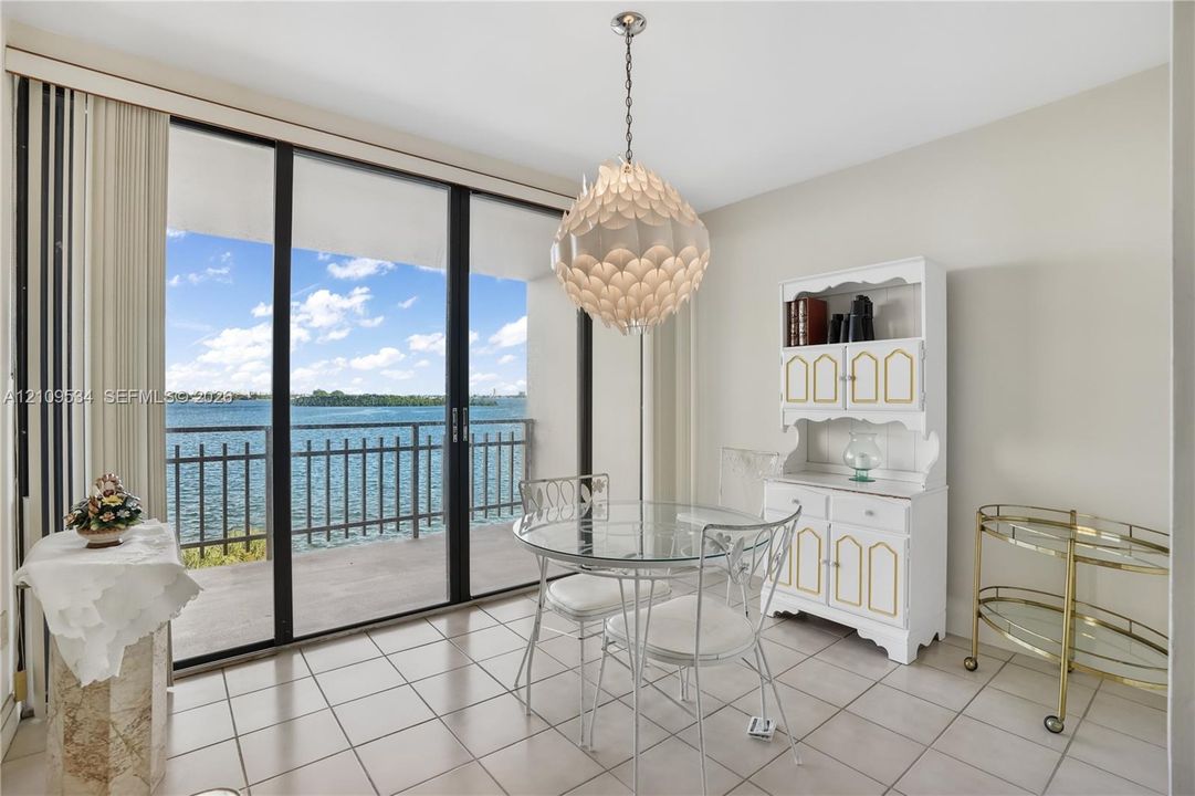 Floor-to-ceiling glass sliding doors opening to a covered balcony, ceramic tile flooring, and decorative tiered pendant lighting