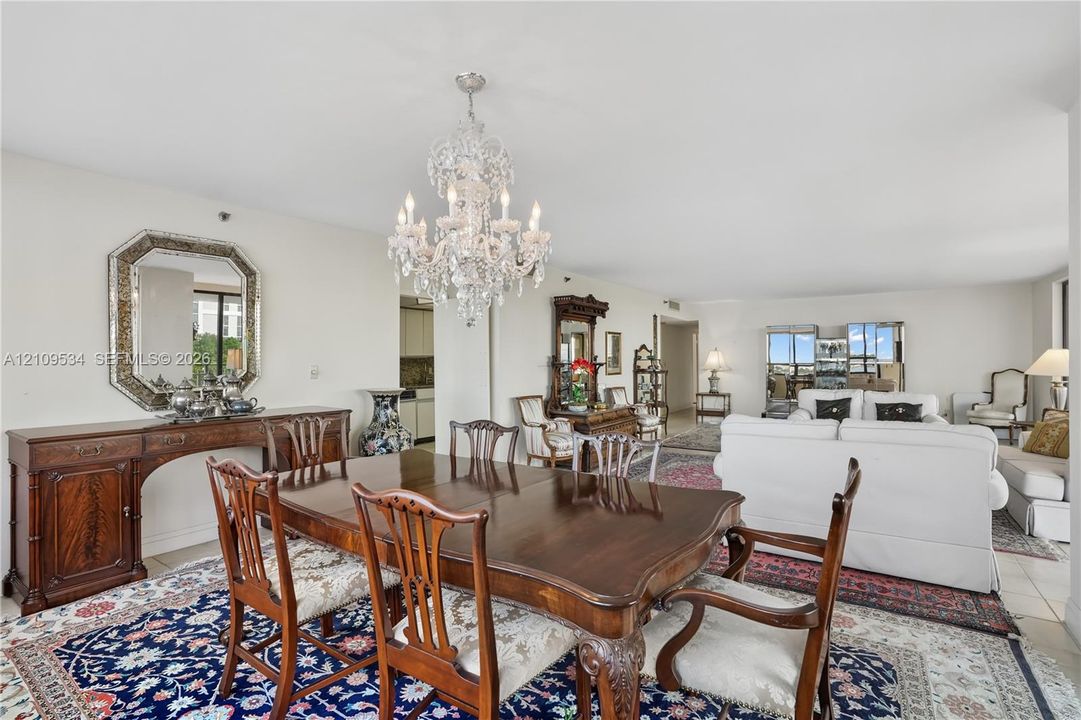 Open-concept living space featuring a tiered crystal chandelier, neutral wall paint, and tile flooring