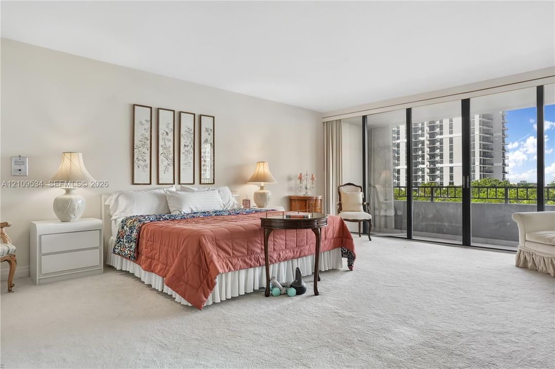Spacious room featuring neutral wall tones, floor-to-ceiling sliding glass doors, and carpeted flooring