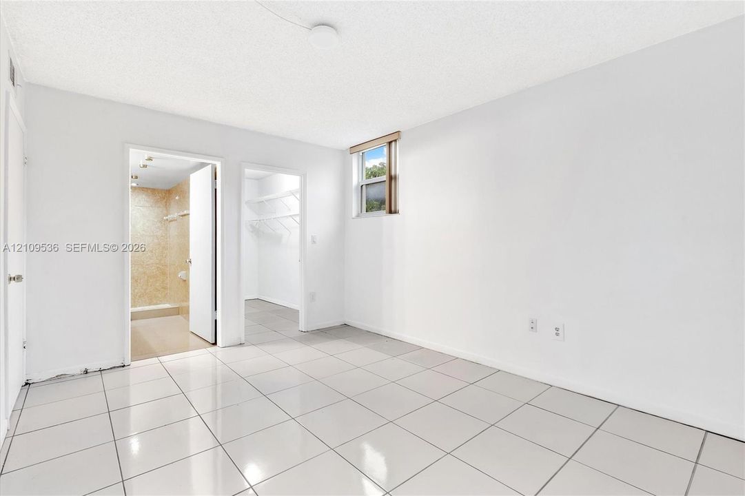 Neutral-toned tile flooring, recessed ceiling lighting, single-pane window, and built-in closet shelving