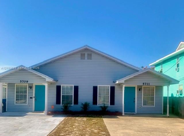 Duplex property featuring light blue siding, white trim, contrasting teal entry doors, and black window shutters