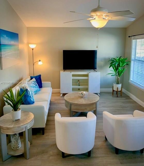 Recessed lighting, ceiling fan with integrated light, wood-finish flooring, window with blinds, and built-in media console