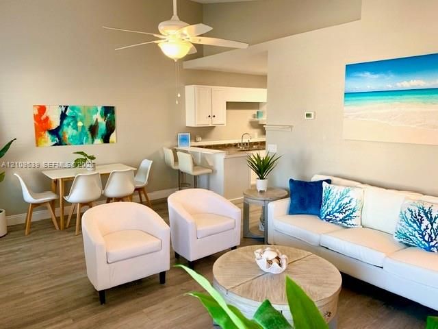 Open-concept living space with wood-finish flooring, vaulted ceilings, and a ceiling fan