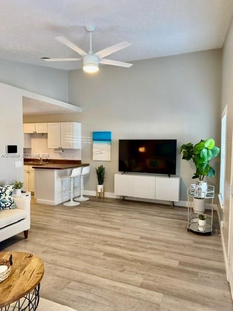 Vaulted ceilings, wood-finish flooring, and a modern ceiling fan with integrated lighting