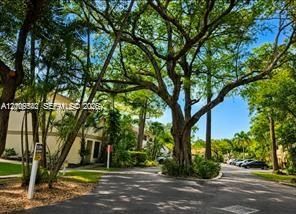 Exterior setting featuring mature trees, paved driveway, and established landscaping
